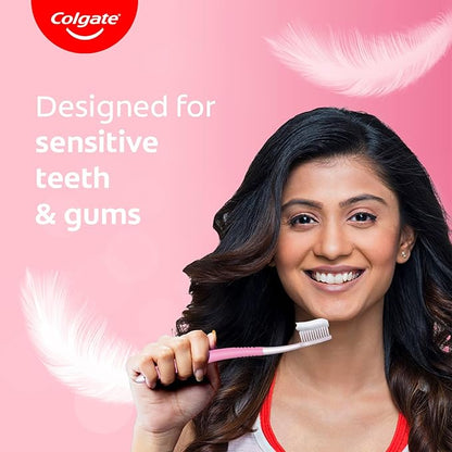 Woman holding a Colgate toothbrush with text 'Designed for sensitive teeth & gums' on a pink background