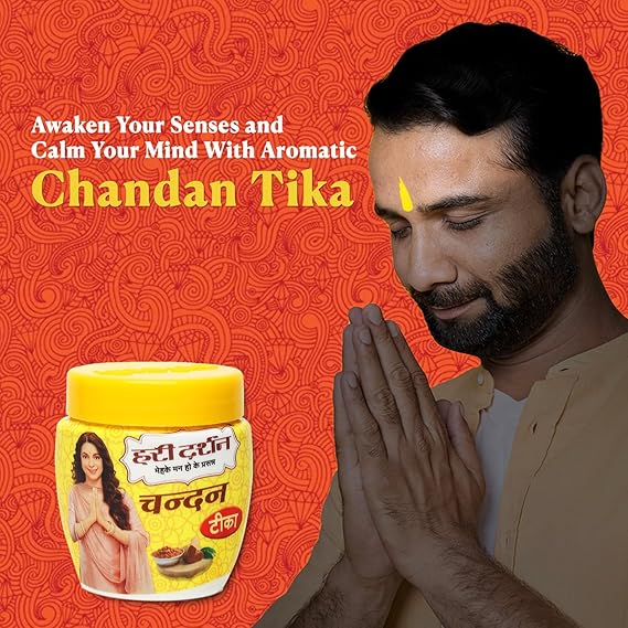 Man with hands in prayer position next to a jar of Chandan Tika on an orange background