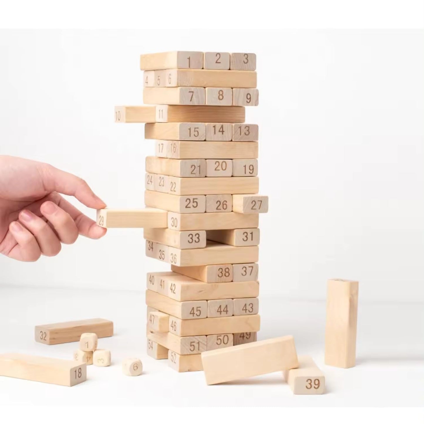 Hand playing with a tower of numbered wooden blocks on a white background